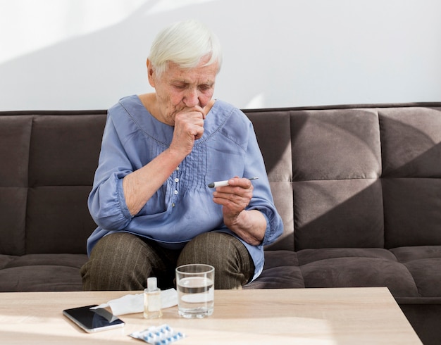 Vooraanzicht van oudere vrouw die thermometer bekijkt