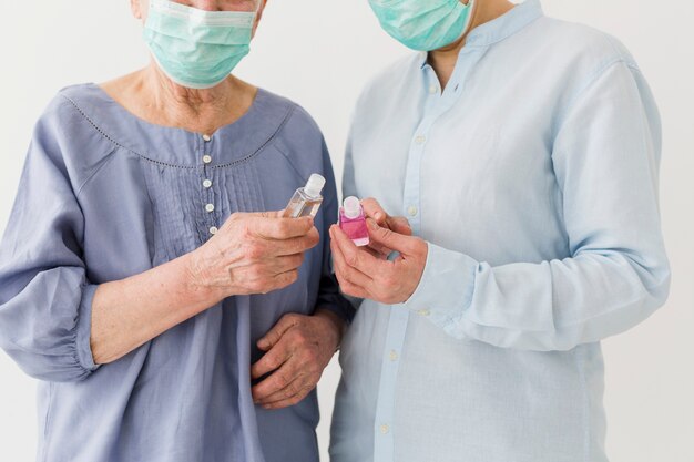 Vooraanzicht van oudere vrouwen die met medische maskers handdesinfecterend middel houden