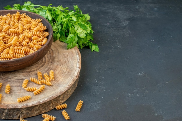 Gratis foto vooraanzicht van rauwe pasta's binnen en buiten bruine pot groene bundel aan de rechterkant op donkerblauwe kleur achtergrond