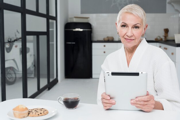 Vooraanzicht van rijpe vrouw in de tablet van de badjasholding