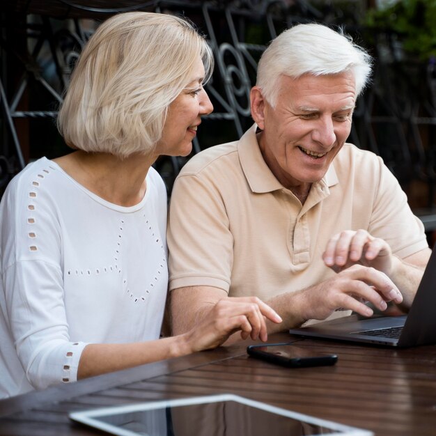 Vooraanzicht van senior paar in de stad met laptop en tablet