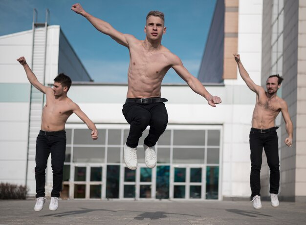 Vooraanzicht van shirtless hiphopartiesten die samen buiten dansen