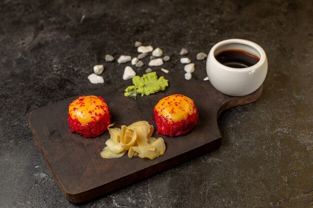 Vooraanzicht van smakelijke de vissenbroodjes van de sushimaaltijd met vissen en rijst samen met saus op grijze muur