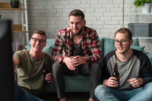 Vooraanzicht van smiley mannelijke vrienden kijken naar sport op tv