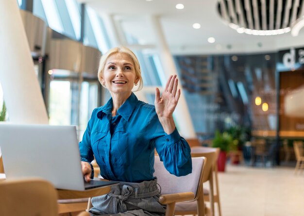 Vooraanzicht van smiley oudere zakenvrouw die om de rekening vraagt tijdens het werken op laptop