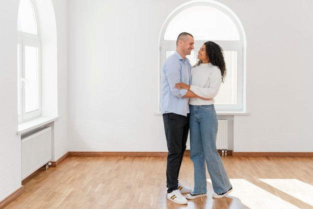 Vooraanzicht van smileypaar in hun nieuwe lege huis met exemplaarruimte