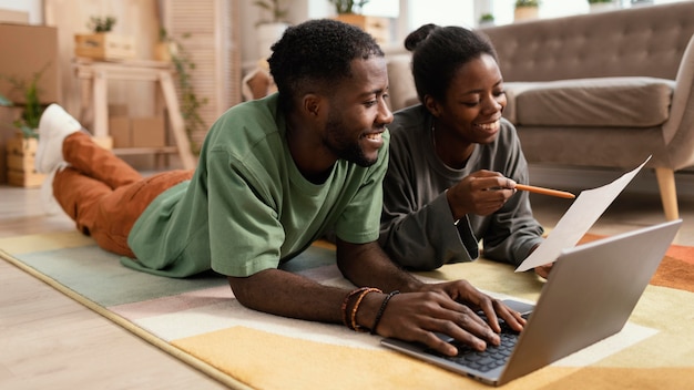 Gratis foto vooraanzicht van smileypaar op de vloer die plannen maken om huis met laptop opnieuw in te richten