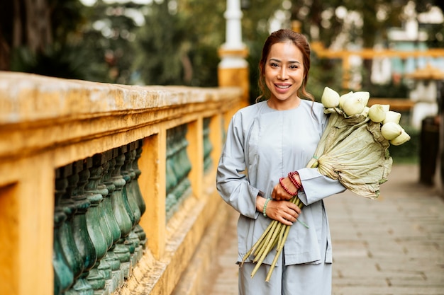 Vooraanzicht van smileyvrouw bij de tempel met boeket bloemen