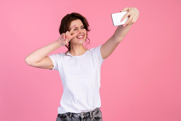 Vooraanzicht van smileyvrouw die een selfie neemt en vredesteken maakt