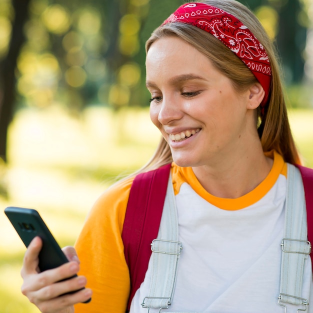 Vooraanzicht van smileyvrouw die smartphone in openlucht bekijken