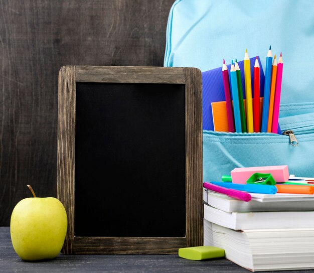 Vooraanzicht van terug naar schoolkantoorbehoeften met appel en bord