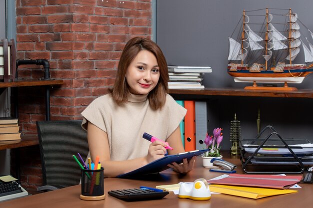 Vooraanzicht van tevreden vrouw die markeerstift gebruikt die aan de muur zit