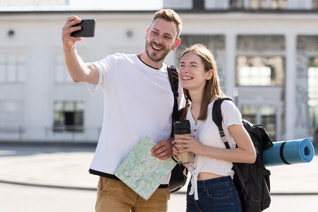 Vooraanzicht van toeristenpaar in openlucht met rugzakken die selfie nemen