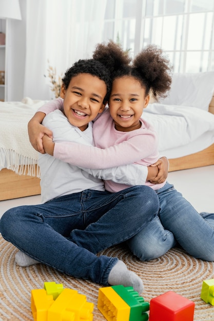 Gratis foto vooraanzicht van twee smileysiblings die elkaar thuis omhelzen