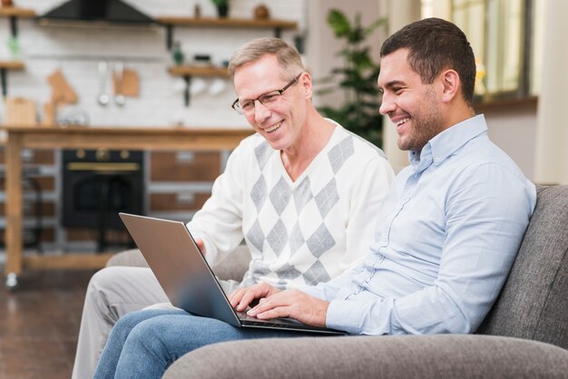 Vooraanzicht van vader en zoon die laptop bekijken