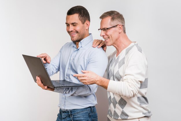 Gratis foto vooraanzicht van vader en zoon die laptop bekijken