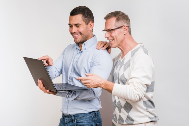 Vooraanzicht van vader en zoon die laptop bekijken