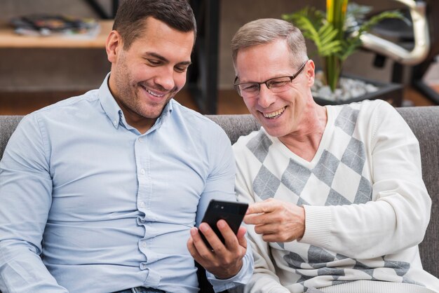 Vooraanzicht van vader en zoon kijken naar de telefoon