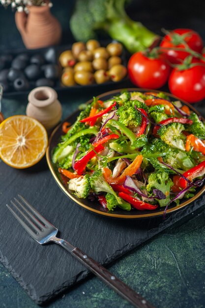 Vooraanzicht van veganistische salade met verse ingrediënten in een bord op zwarte snijplank