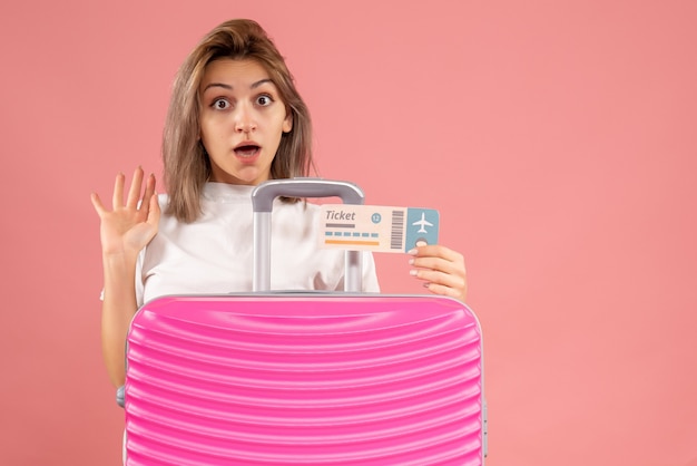 Gratis foto vooraanzicht van verbaasde jonge vrouw met het roze kaartje van de kofferholding