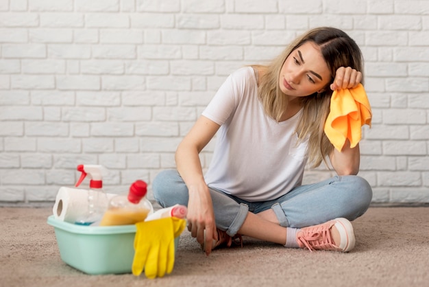 Gratis foto vooraanzicht van vermoeide vrouw met schoonmaakproducten en doek