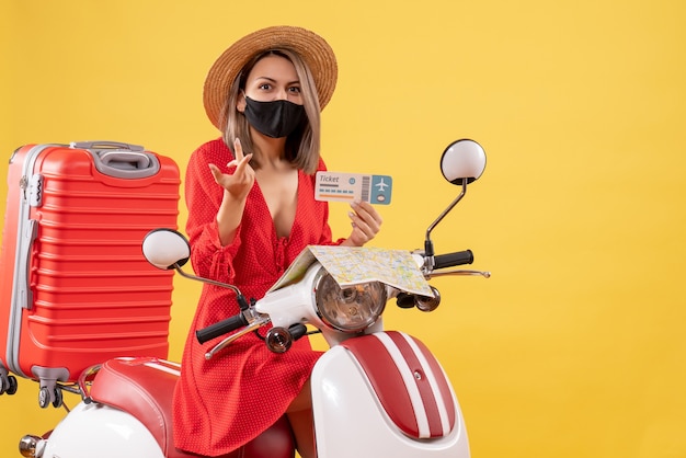 Vooraanzicht van verwarde jonge dame met zwart masker op kaartje van de bromfietsholding