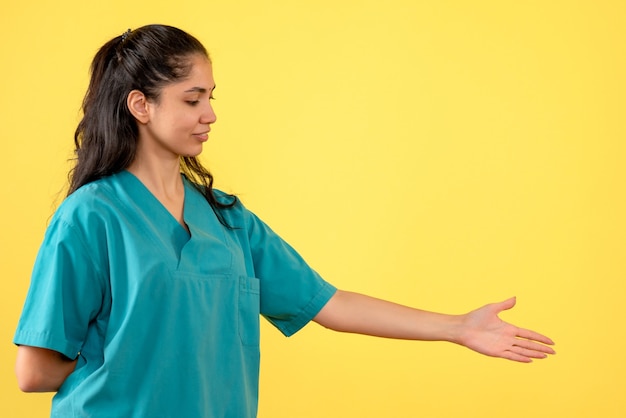 Vooraanzicht van vrij vrouwelijke arts die hand op gele muur geeft