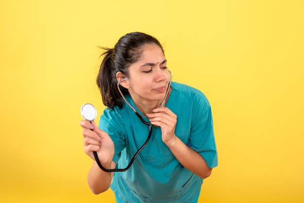 Vooraanzicht van vrij vrouwelijke arts met een stethoscoop op gele muur