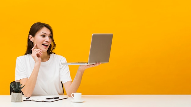 Vooraanzicht van vrouw die bij bureau geniet van wat zij op haar laptop met exemplaarruimte ziet