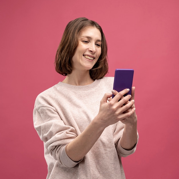 Vooraanzicht van vrouw die en smartphone glimlacht bekijkt