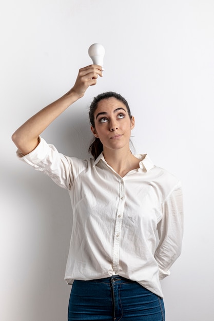 Vooraanzicht van vrouw die gloeilamp boven hoofd houdt