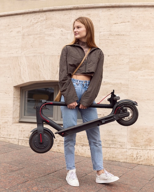 Gratis foto vooraanzicht van vrouw die in openlucht elektrische autoped houdt