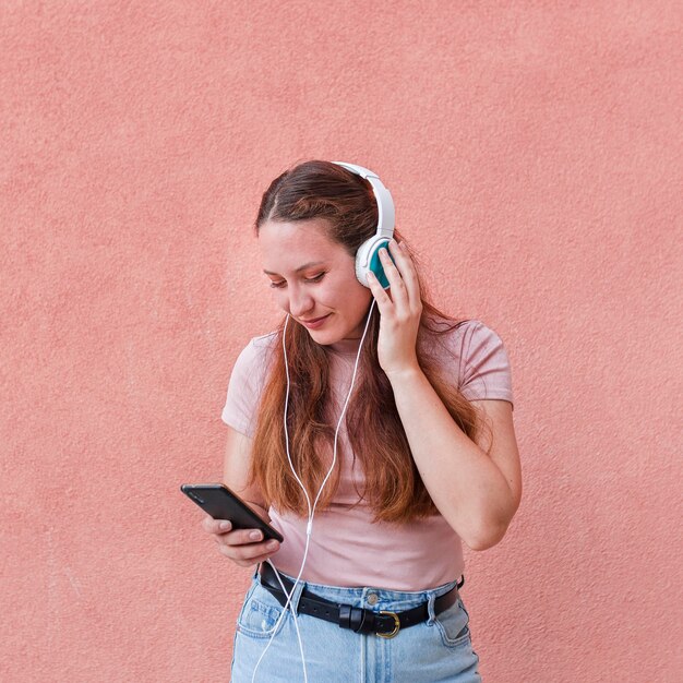 Vooraanzicht van vrouw die smartphone en hoofdtelefoons gebruiken om aan muziek te luisteren