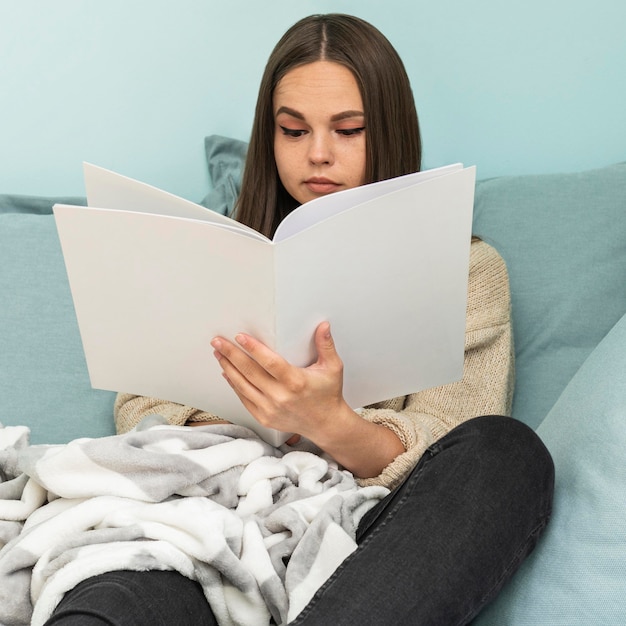 Gratis foto vooraanzicht van vrouw die thuis een boek leest tijdens de pandemie