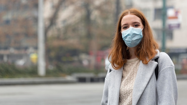 Vooraanzicht van vrouw in de stad die medisch masker met exemplaarruimte draagt