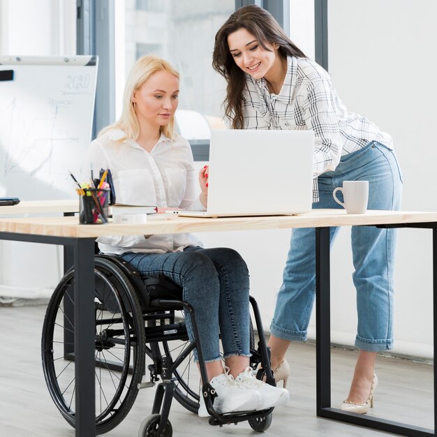 Vooraanzicht van vrouw in rolstoel die bij bureau werkt