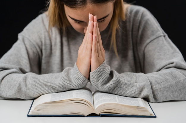 Vooraanzicht van vrouw met bijbel bidden