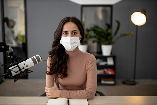 Vooraanzicht van vrouw met een medisch masker in een radiostudio