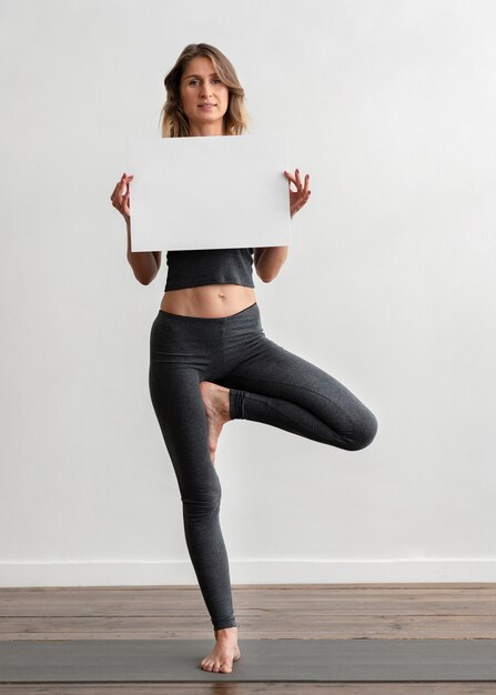 Vooraanzicht van vrouw met lege bordje terwijl thuis yoga doen