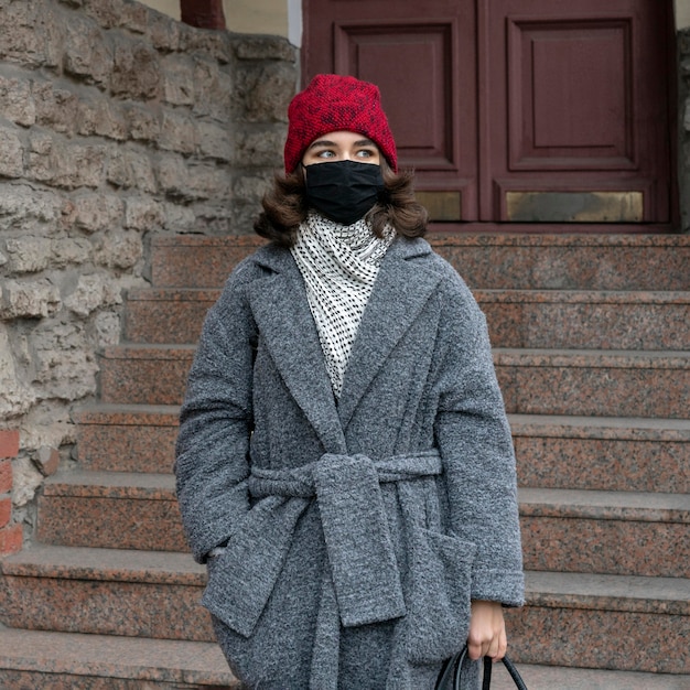 Vooraanzicht van vrouw met medisch masker buitenshuis