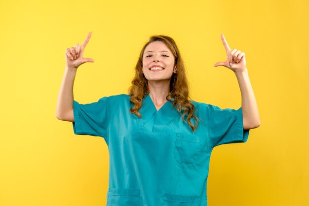 Vooraanzicht van vrouwelijke arts die op gele muur glimlacht