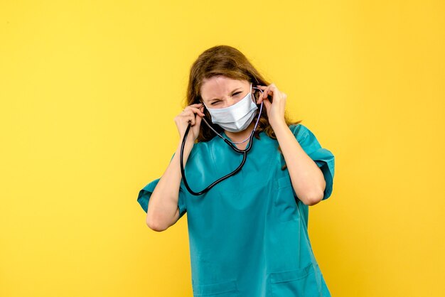 Vooraanzicht van vrouwelijke arts in masker op gele de doktersgezondheid van het vloerziekenhuis