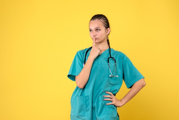 Vooraanzicht van vrouwelijke arts in medisch kostuum op gele muur