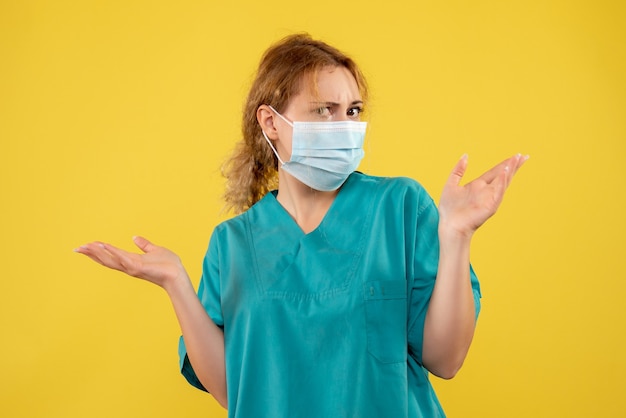 Vooraanzicht van vrouwelijke arts in steriel beschermend masker op gele muur