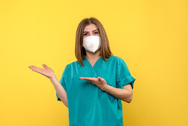 Vooraanzicht van vrouwelijke arts met beschermend masker op gele muur