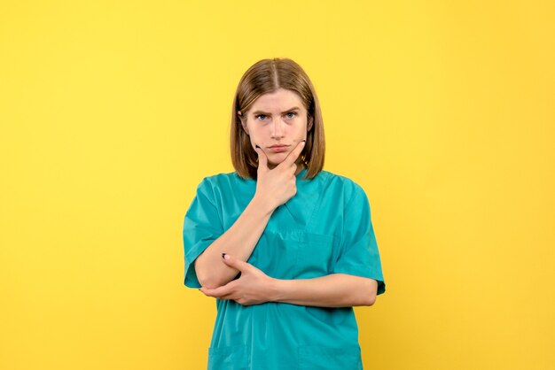 Vooraanzicht van vrouwelijke arts met denkende uitdrukking op gele muur