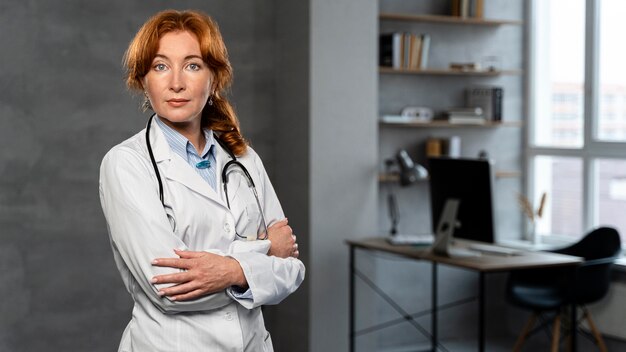 Vooraanzicht van vrouwelijke arts met een stethoscoop poseren in het kantoor