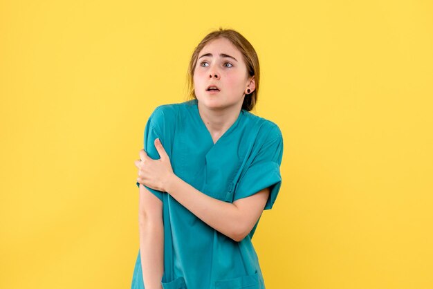 Vooraanzicht van vrouwelijke arts met gekwetste hand op gele muur