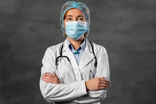 Vooraanzicht van vrouwelijke arts met medisch masker en haarnetje poseren