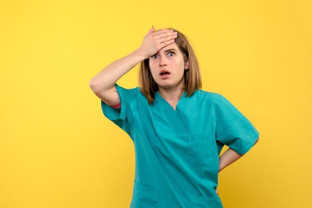 Vooraanzicht van vrouwelijke arts met nerveuze uitdrukking op gele muur